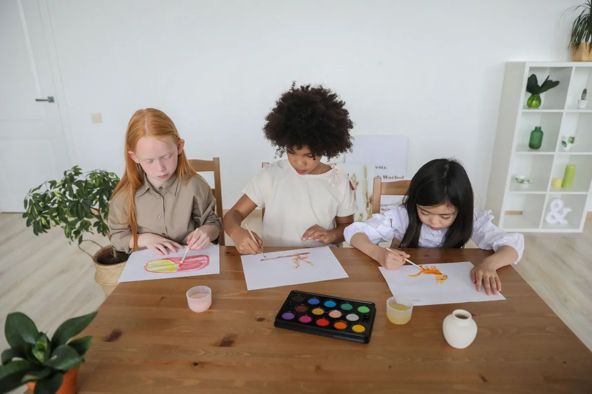 Three children painting with watercolours together at a table
